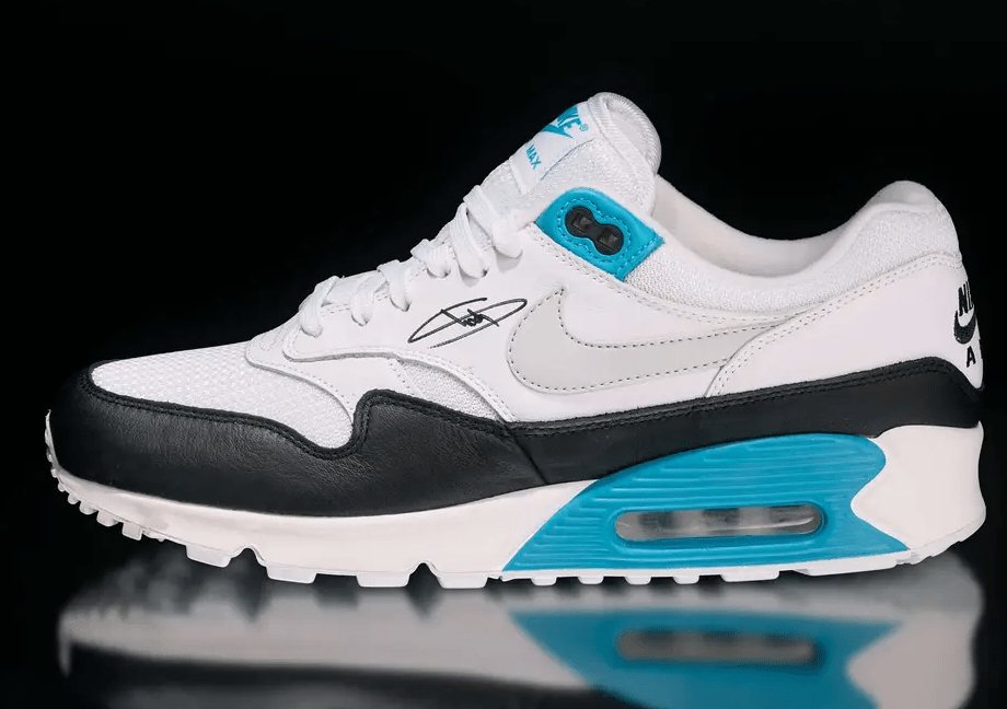 A pair of white and black Nike Air Max 90 sneakers with teal accents and a visible Air Max sole unit.