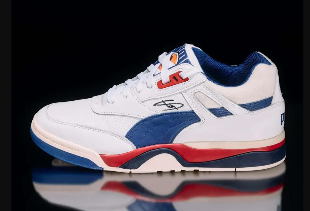 A pair of white and blue athletic shoes with red accents, featuring the Puma logo.