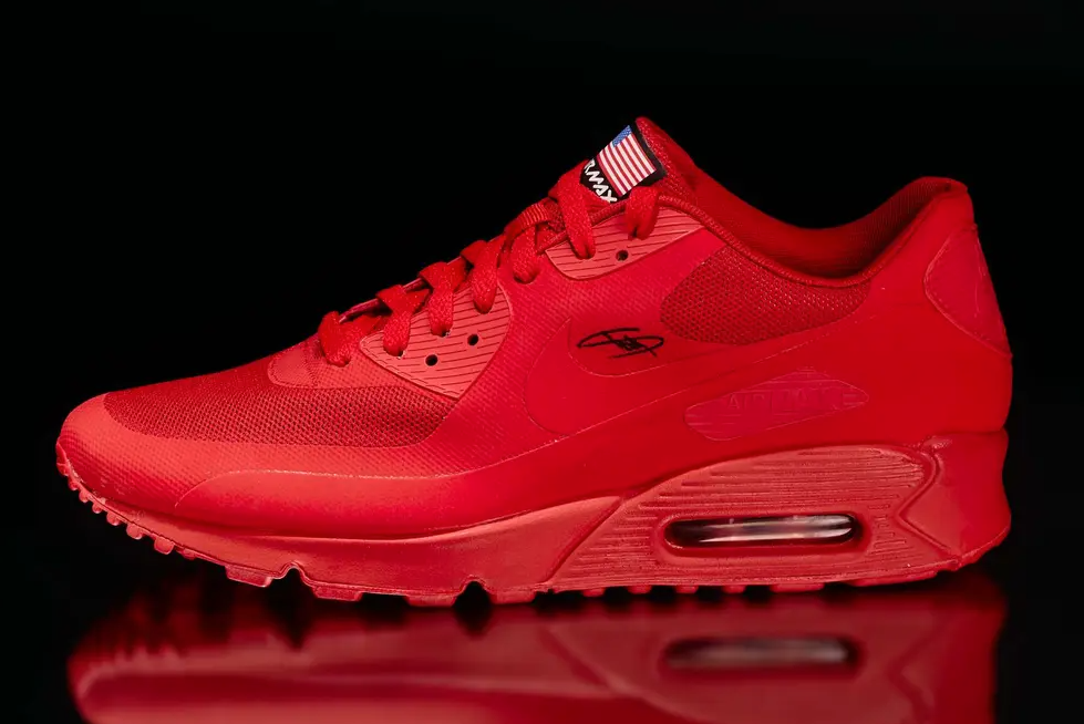 A pair of bright red Nike Air Max 90 sneakers with the Nike logo visible on the side, against a black background.