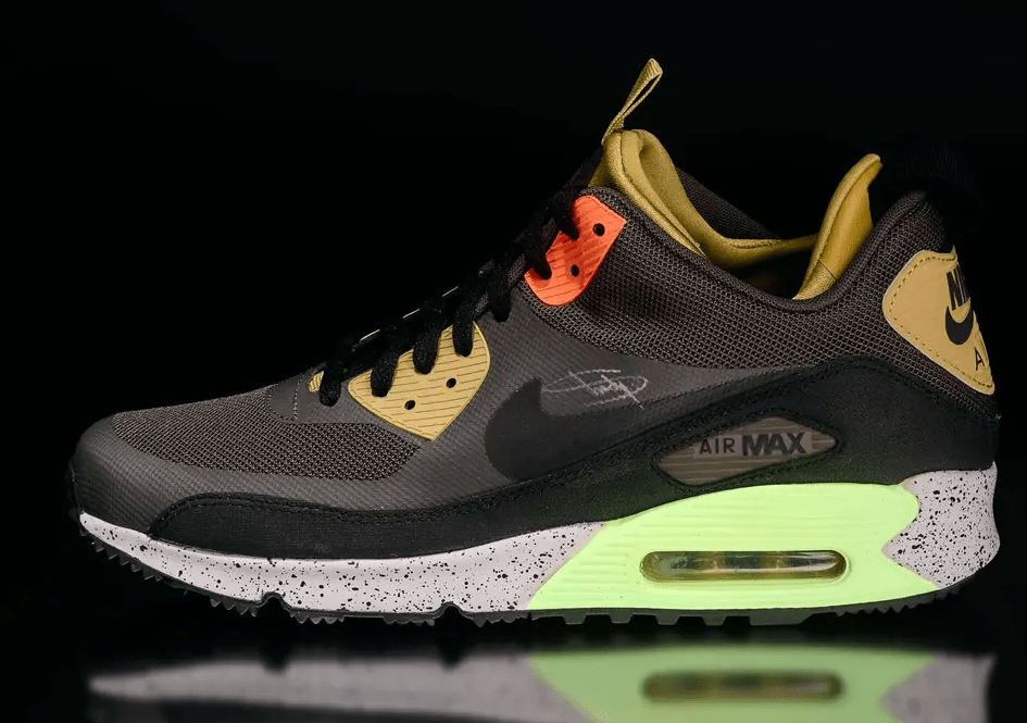 A pair of Nike Air Max 90 sneakers in a dark gray and neon green colorway, with a black mesh upper and visible Air Max cushioning.
