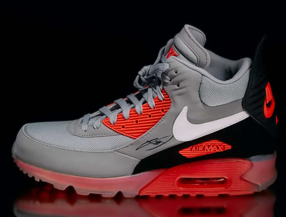 A pair of gray and red Nike Air Max 90 sneakers with visible Air Max branding on the side.