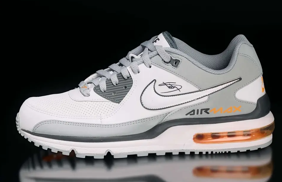A pair of white and gray Nike Air Max sneakers with visible air cushioning and orange accents.