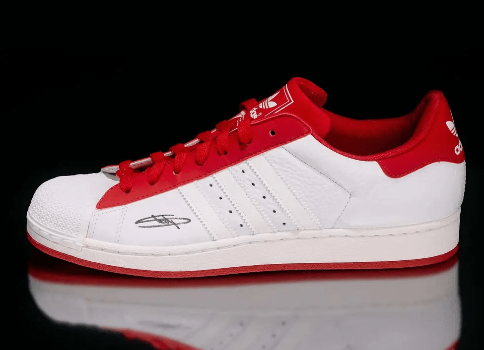 A white and red Adidas Superstar sneaker with the Adidas logo visible on the side.