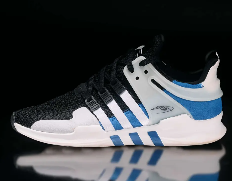 A black and white sneaker with blue accents and the Adidas logo.