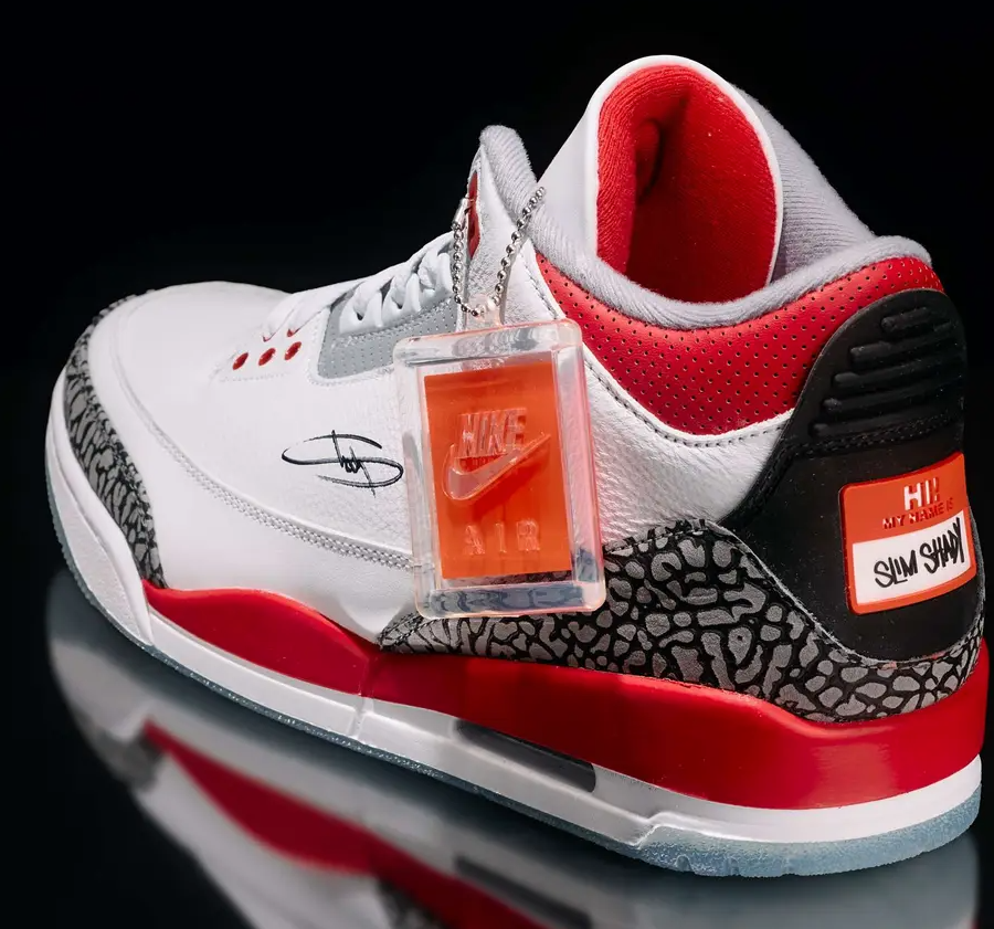 A pair of white and red Nike Air Jordan 3 sneakers with a Nike Air logo, "Slim Shady" text, and an orange Nike Air tag.