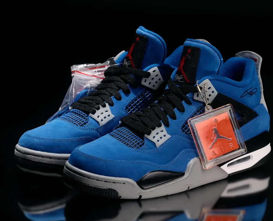 A pair of blue and black Nike Air Jordan 4 sneakers with red accents, displayed on a reflective surface against a black background.