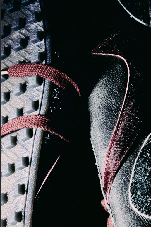 Close-up view of black and pink sneaker with laces and tread pattern.
