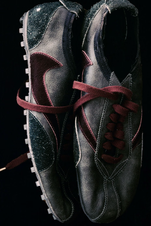 A pair of black and gray leather hiking boots with red laces, against a dark background.