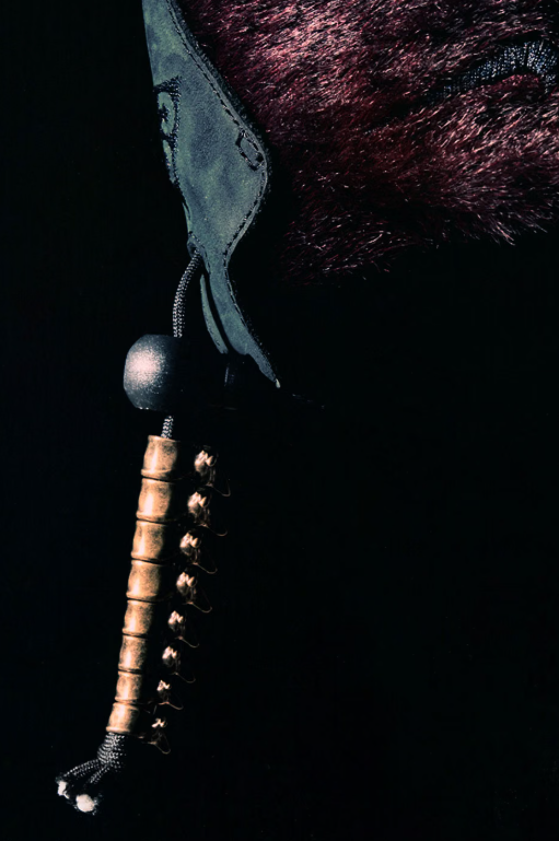 A close-up view of a black and silver knife with a serrated edge and a wooden handle against a dark, textured background.