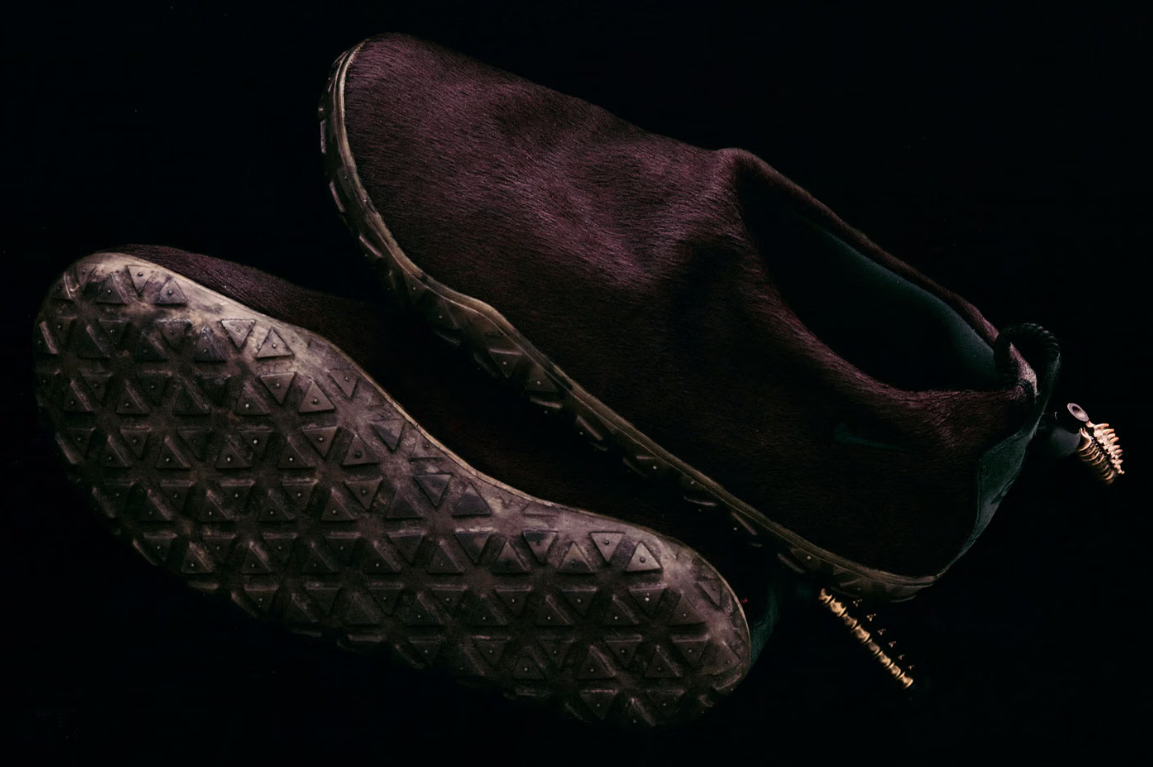 A pair of dark brown boots with a rugged, textured sole pattern against a black background.