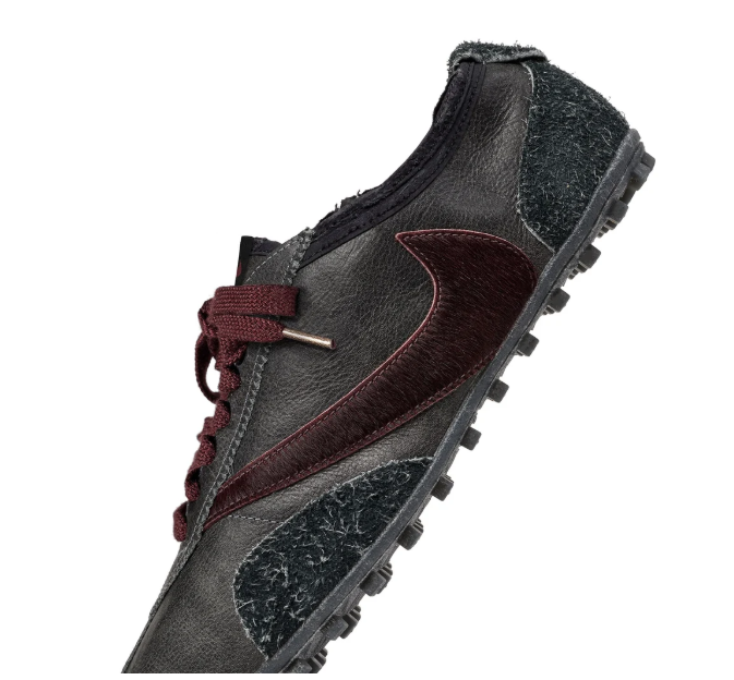 A close-up view of a black and burgundy leather hiking boot with a rugged sole and laces.
