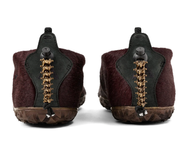 A pair of burgundy fur-lined boots with gold-colored metal accents on the sides.