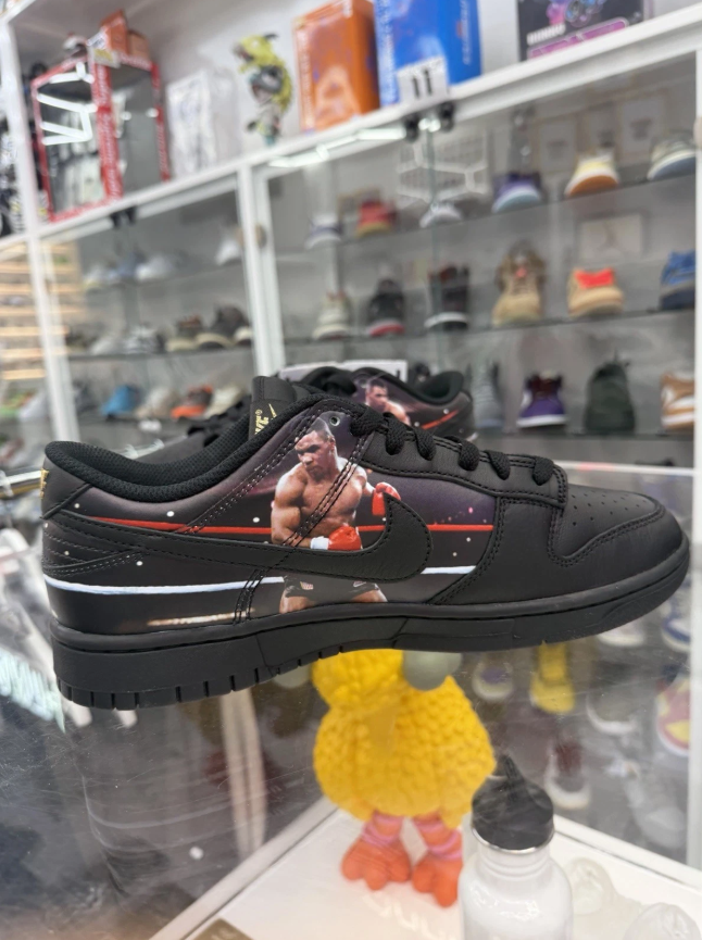 A pair of black and red Nike sneakers displayed on a shelf with various other shoes and accessories.