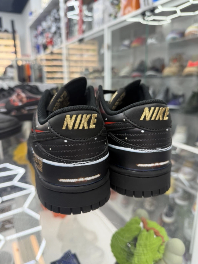A pair of black Nike sneakers with gold branding and thick soles on display in a retail setting.