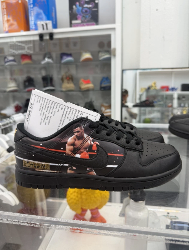 A pair of black sneakers with a boxing-themed design, featuring a boxer image and text on the side.
