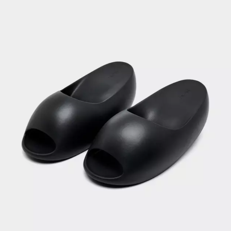 A pair of black, slip-on shoes or sandals against a plain white background.