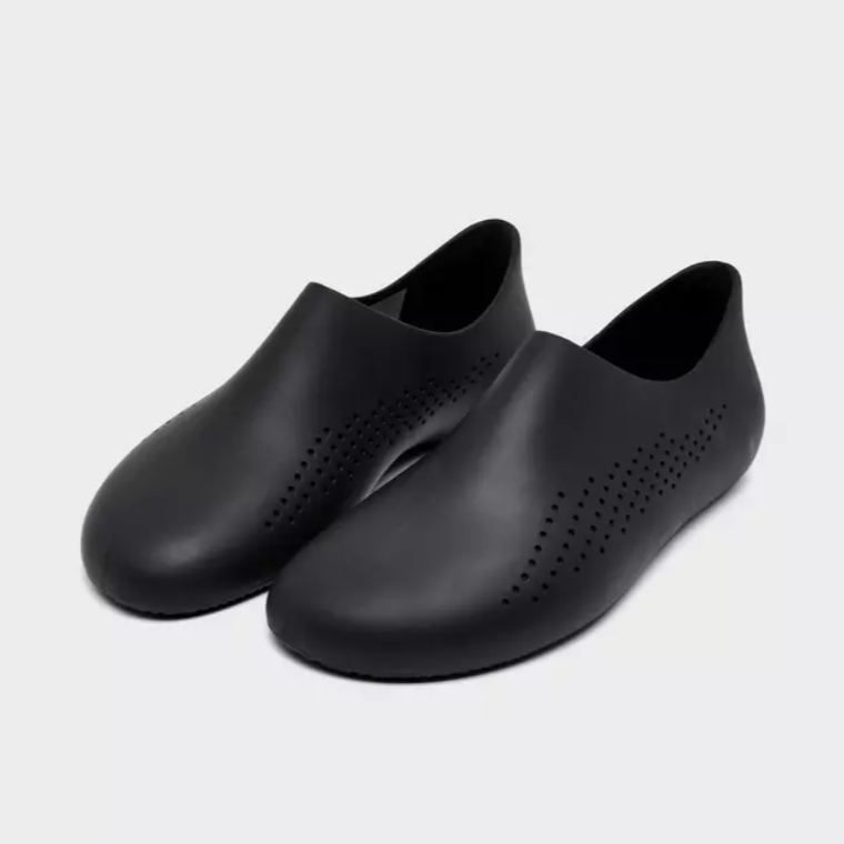 A pair of black slip-on shoes with perforated patterns on the surface.