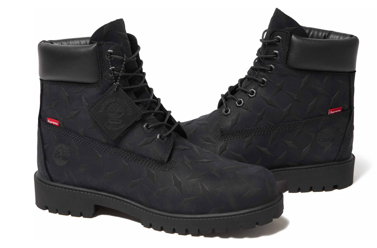 Black Timberland-style boots with a textured, camouflage-like pattern and red accents.