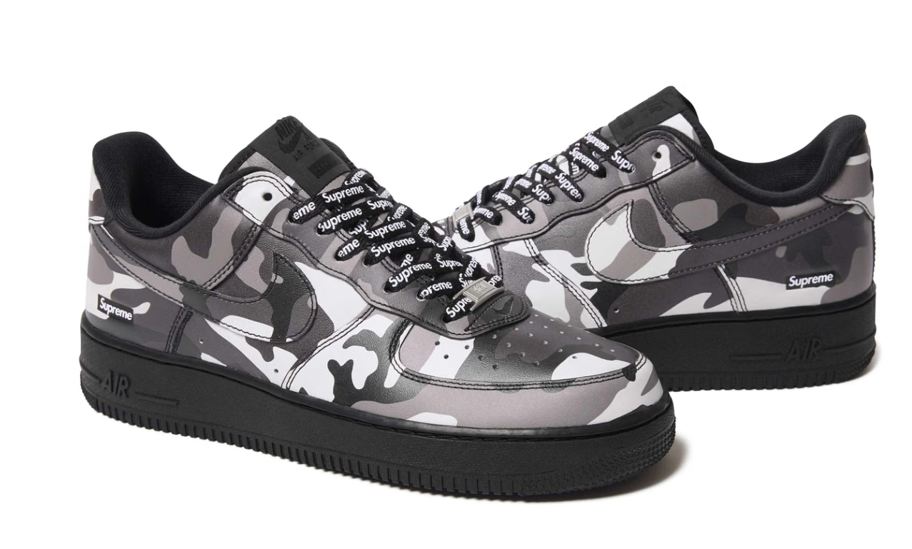 Pair of black and gray camouflage-patterned Nike Air Force 1 sneakers with Supreme branding.
