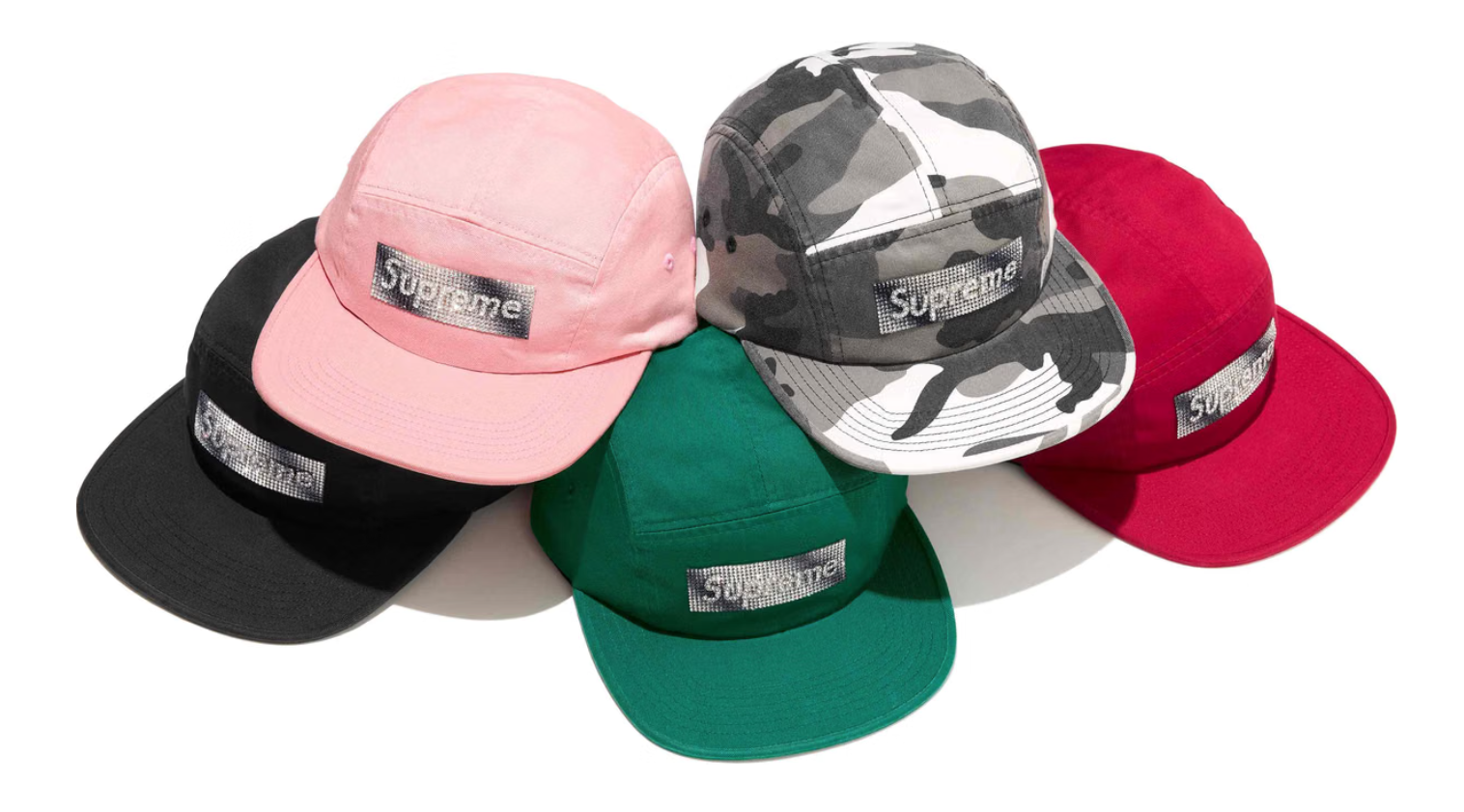 Assortment of Supreme-branded baseball caps in various colors and camouflage patterns.