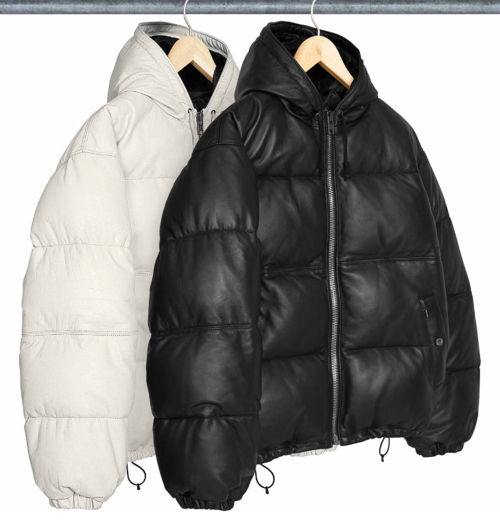 Two puffy black and white winter jackets hanging on a metal rack.
