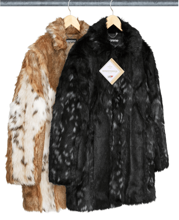 Two fur coats hanging on a clothing rack, one black and one brown and white spotted.