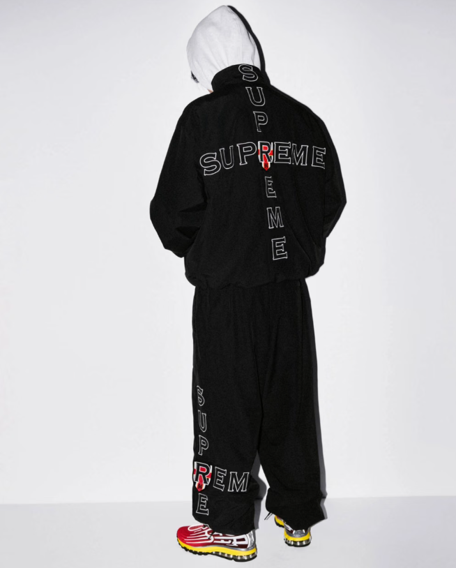 A person wearing a black hooded sweatshirt with the text "SUPREME" printed on the back.