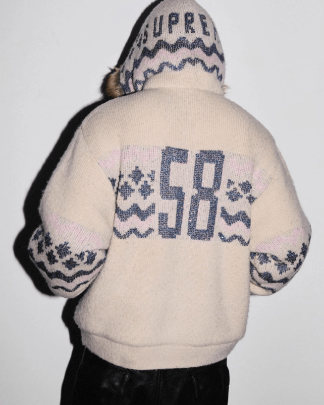 A person wearing a white sweater with the text "CO 58" printed on the back.