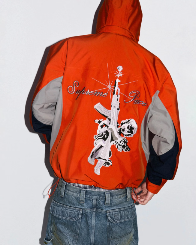 A person wearing a red hooded jacket with a graphic design featuring a skull and the text "Supreme Nica".