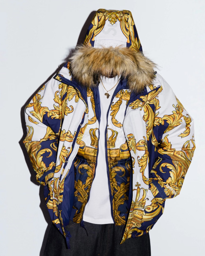 A white and navy blue hooded jacket with an ornate gold and blue floral pattern.