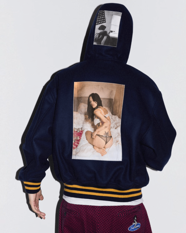 A person wearing a navy blue hooded sweatshirt with a photo of a woman in lingerie printed on the back.