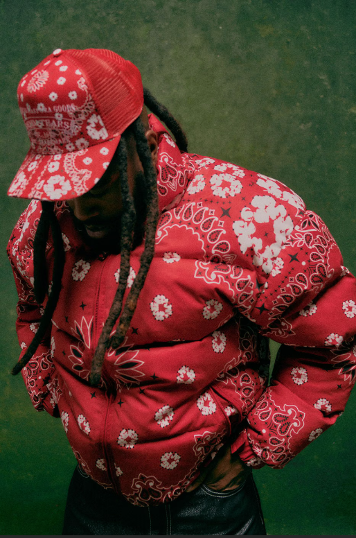A person wearing a red floral-patterned jacket and matching hat with a brim.