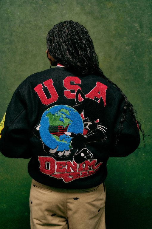A person wearing a black jacket with "USA DENIM" and a globe graphic printed on the back.