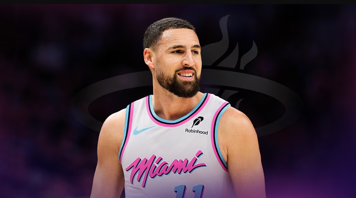 A basketball player wearing a Miami jersey with the number 11 on it, smiling and looking directly at the camera.