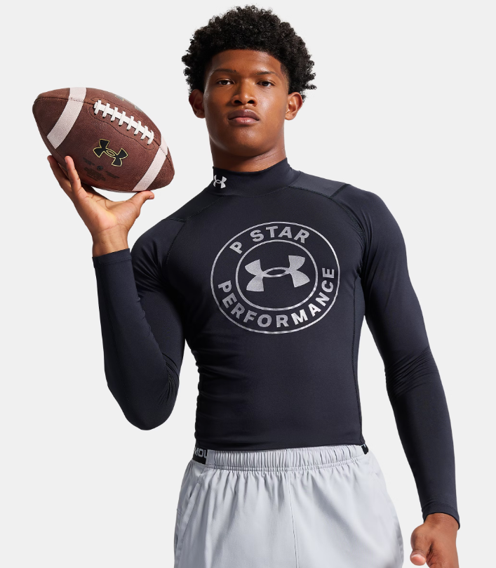 A young Black man wearing an Under Armour shirt and holding a football.