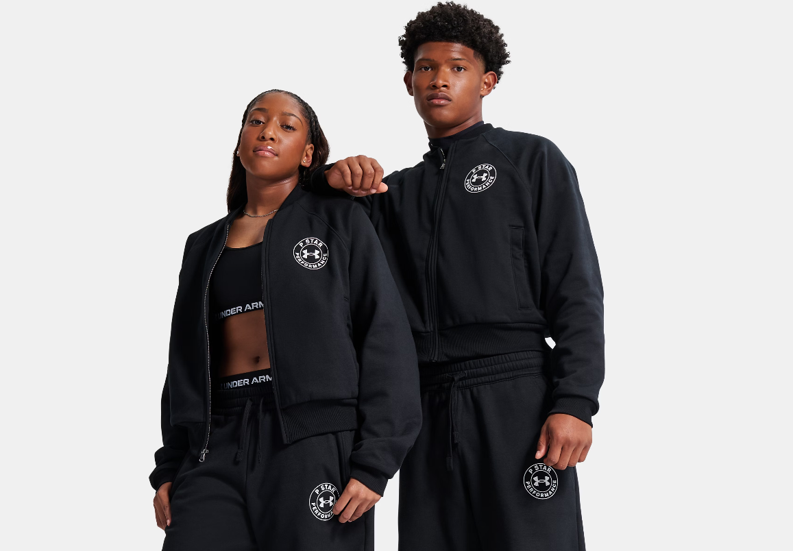 Two people wearing black Under Armour jackets and pants standing together against a white background.