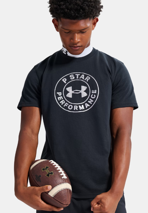 A young man wearing a black t-shirt with the "P STAR PERFORMANCE" logo, holding a football.