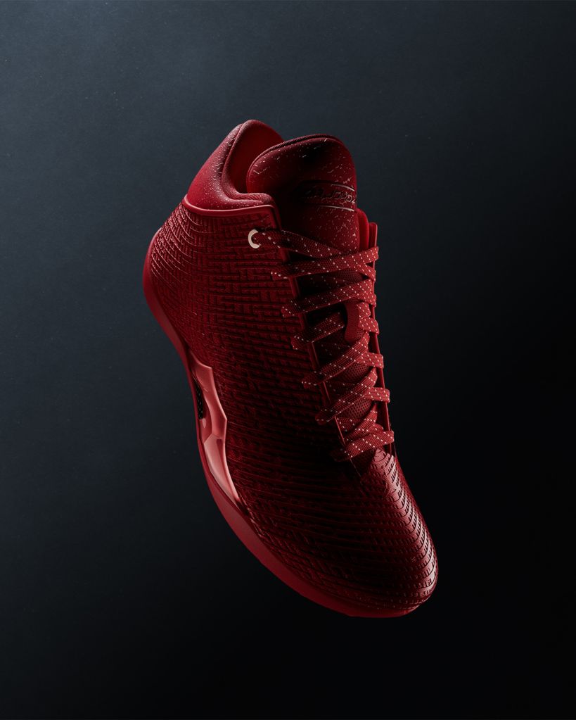 A close-up view of a red sneaker with a textured, patterned upper and a bright red sole.