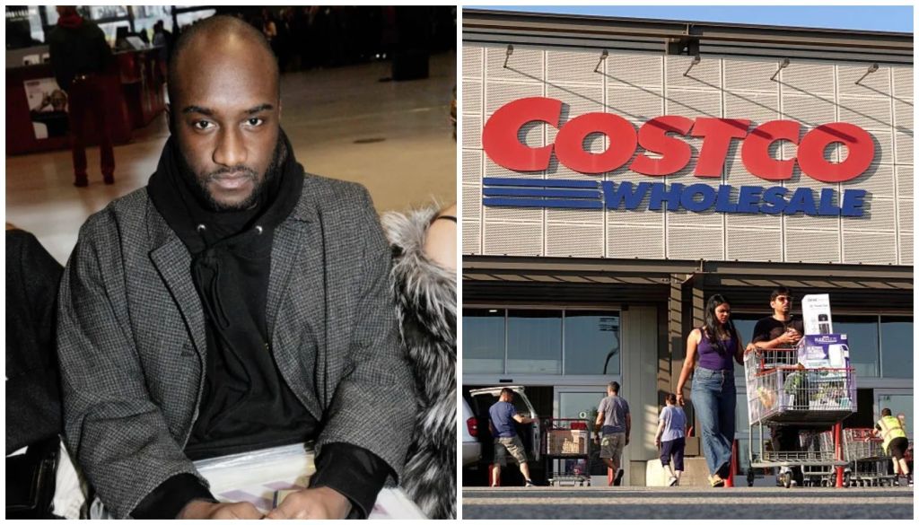 A man in a gray coat stands outside a Costco wholesale store, with customers visible inside the store.